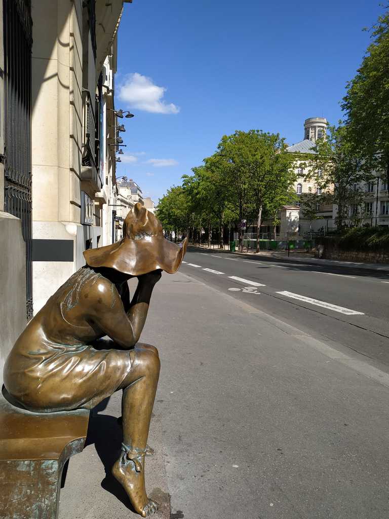 a statue representing a woman waiting on a bench
